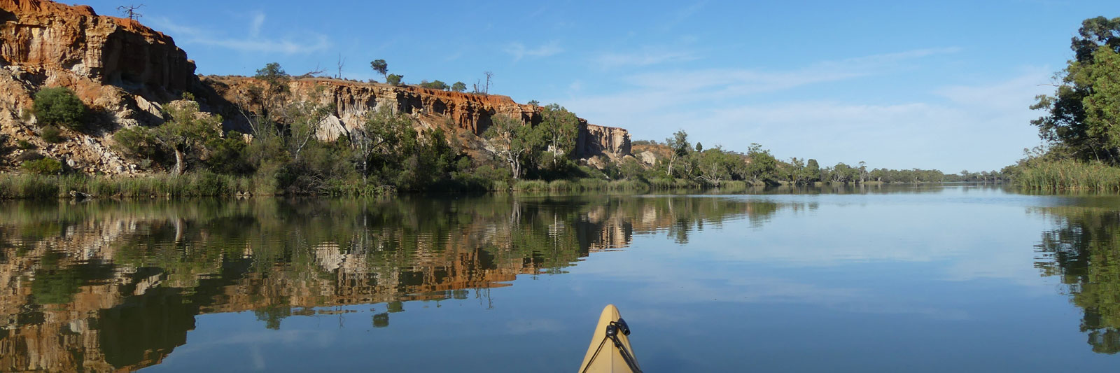 Paddling wide river surrounded by cliffs and trees
