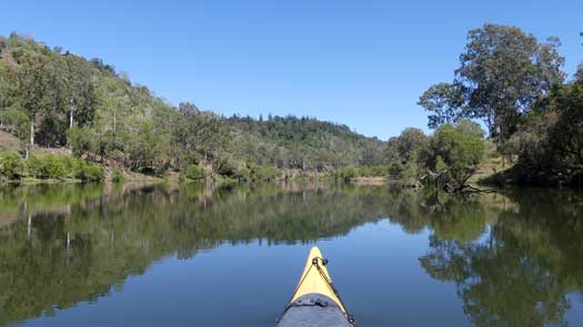 Kayak on a calm river with reflections.