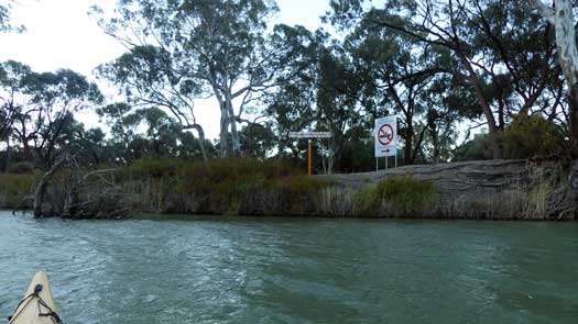 Border signs on riverbank