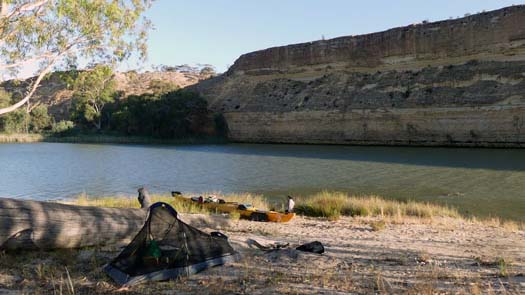 Tent on a beach beside the river and tall cliff