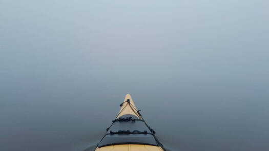 kayaker with nothing to distinguish the water from the fog